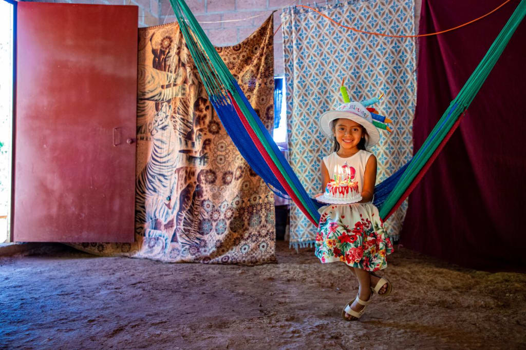 A girl sits in a hammock in a birthday hat
